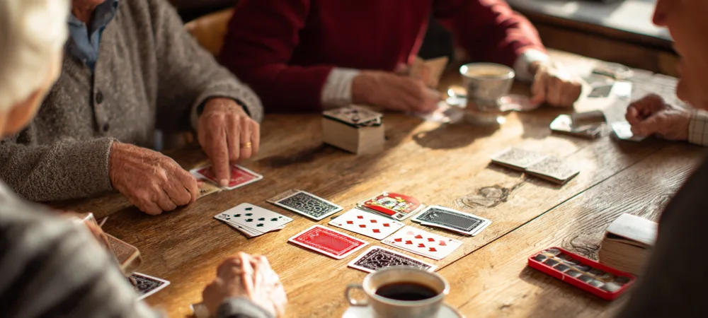a group of people sitting at a table playing canasta