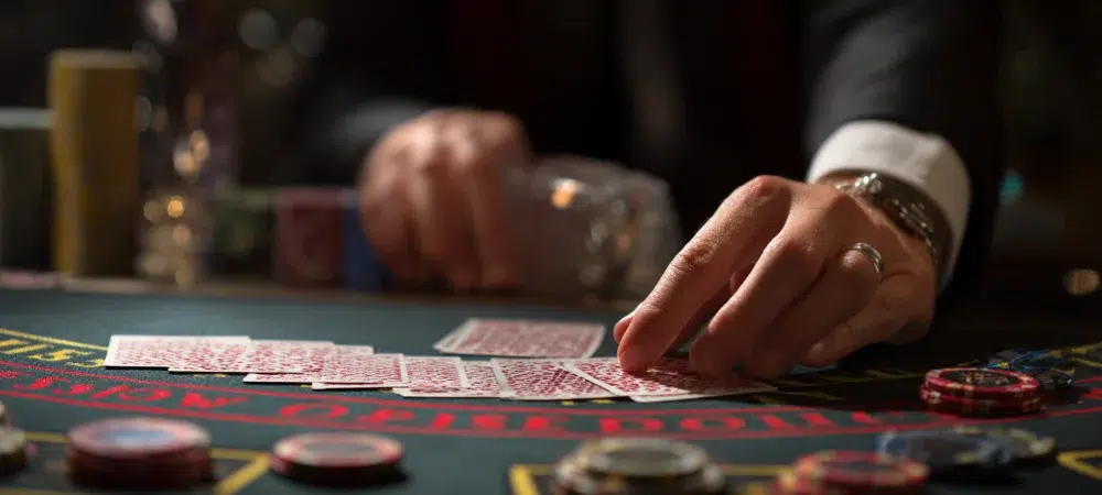 a person picking a card on a blackjack table